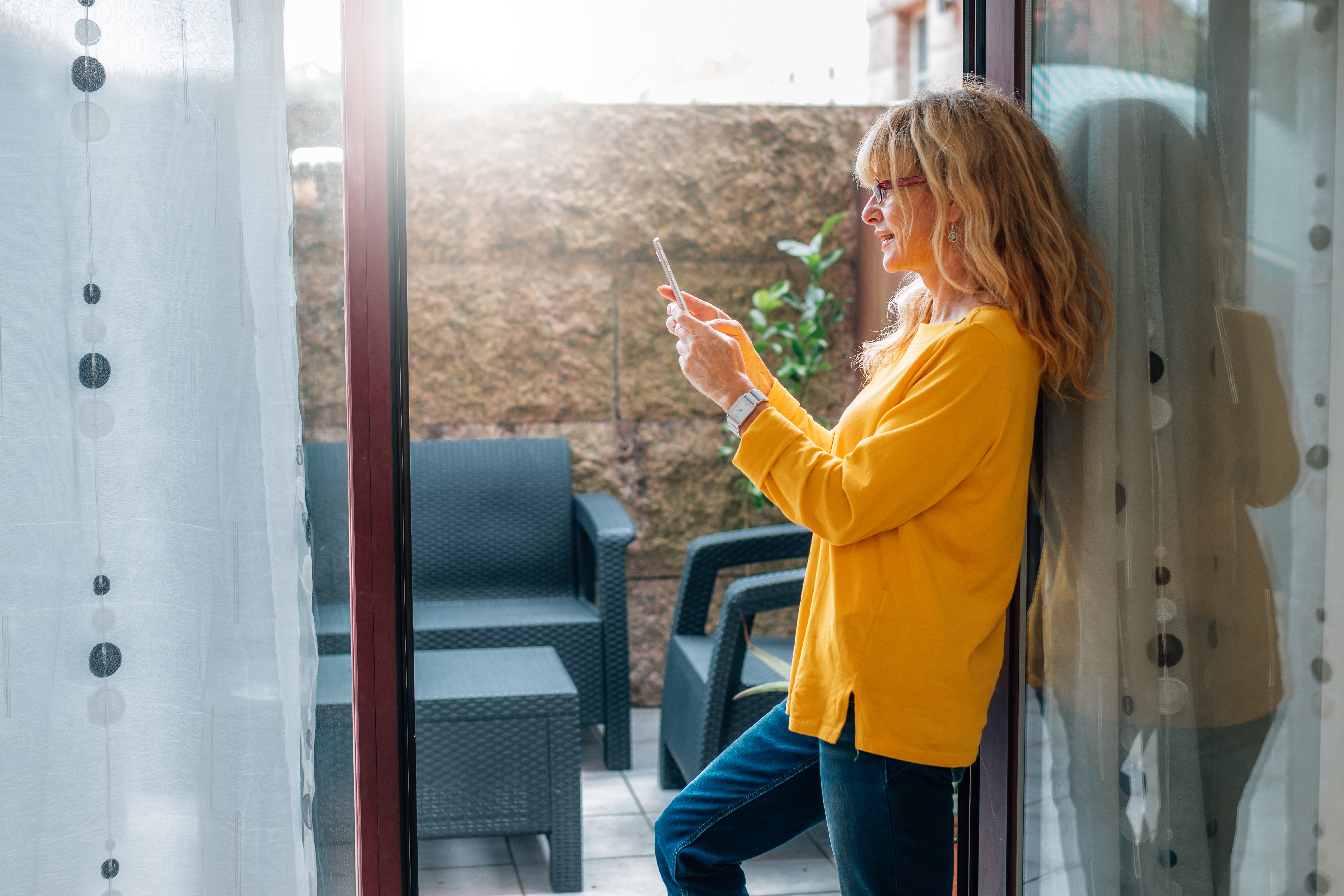 Image of woman standing at her apartment balcony door