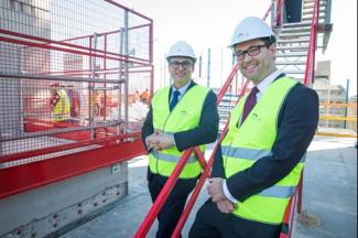 Two men in hard hats and high-visibility jackets on a work site