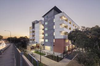 Front view of a grey, white and brick apartment block