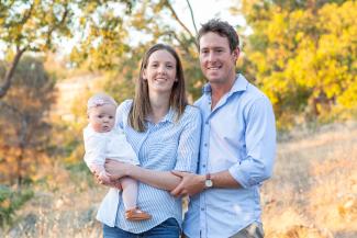 Woman holding baby and man smiling