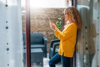 Image of woman standing at her apartment balcony door