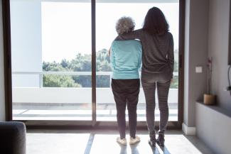 two women, one with arm around the other looking out a window